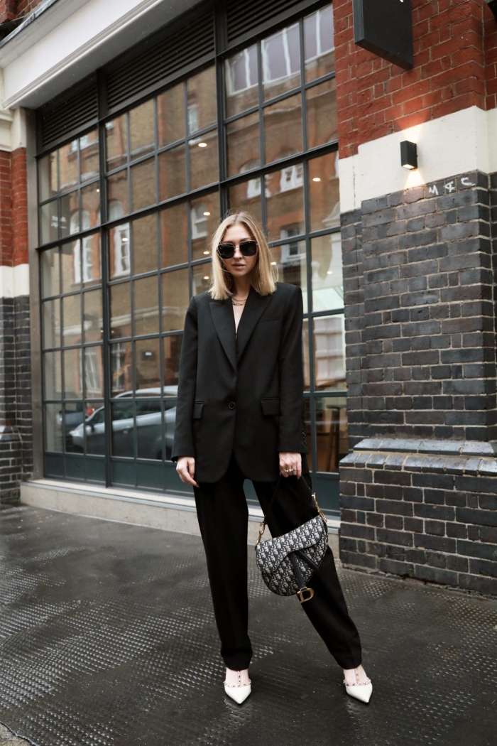 idée de tenue femme stylée en costume oversize de couleur noir assortie avec paire de chaussures blanches, modèle de pantalon tailleur femme