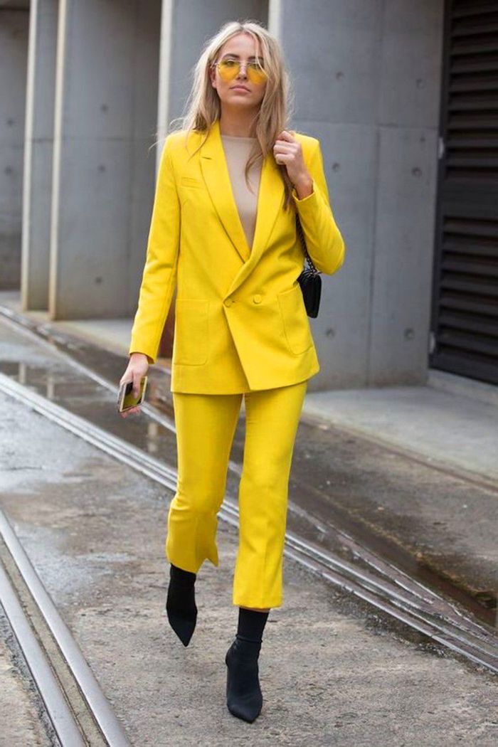 ensemble tailleur femme chic en couleur jaune illumineuse pantone 2021 des bottes noires et lunette tintes