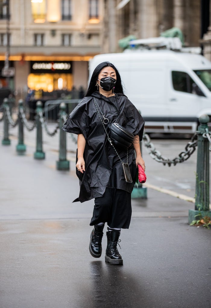 bottine doc martens avec une veste noir avantgardiste et moderne une femme avec une masque sur le visage